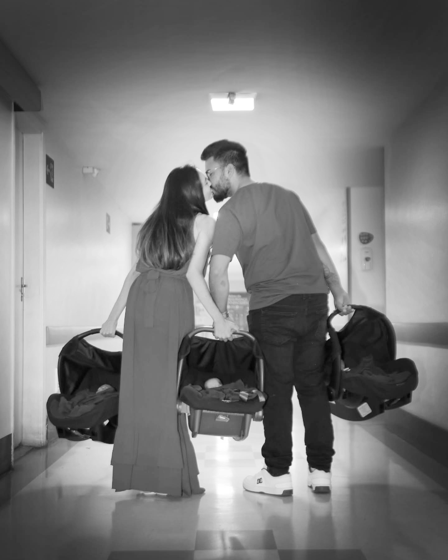 Parents kissing as they leave hospital with newborn baby