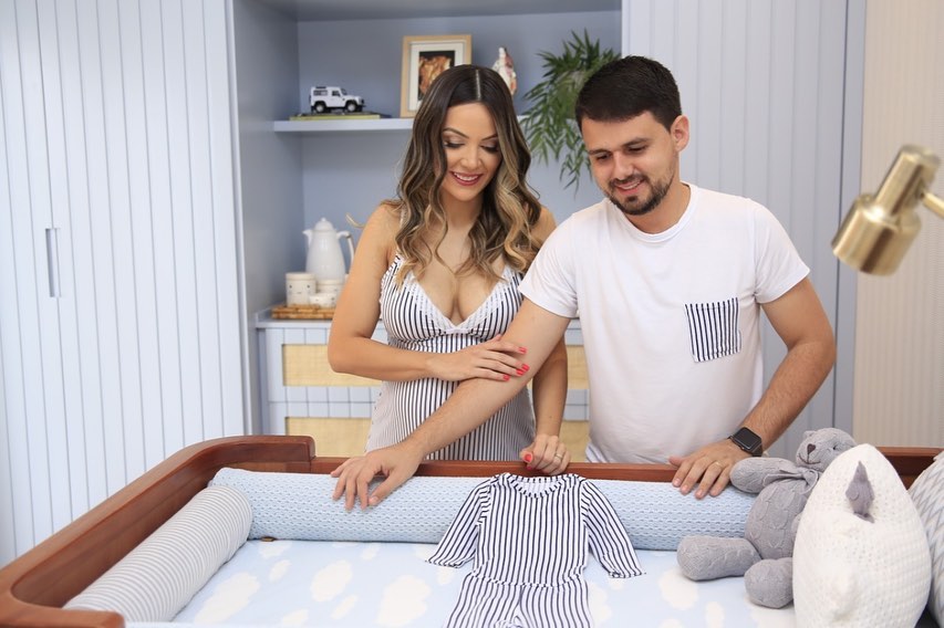Artistic photograph of pregnant woman with partner and baby clothes