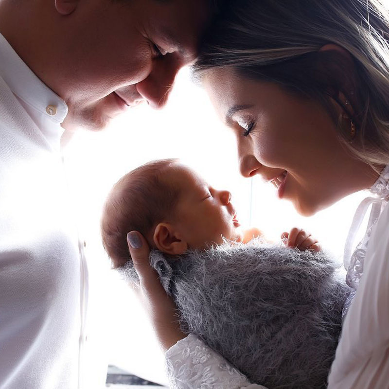 Young parents cradling their newborn baby