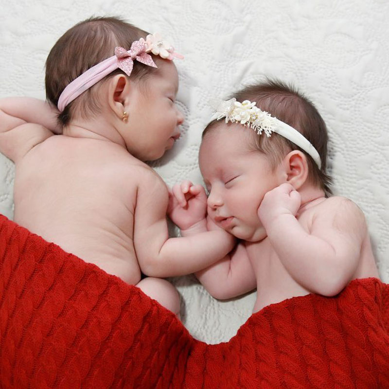 Two newborn babies in a red blanket